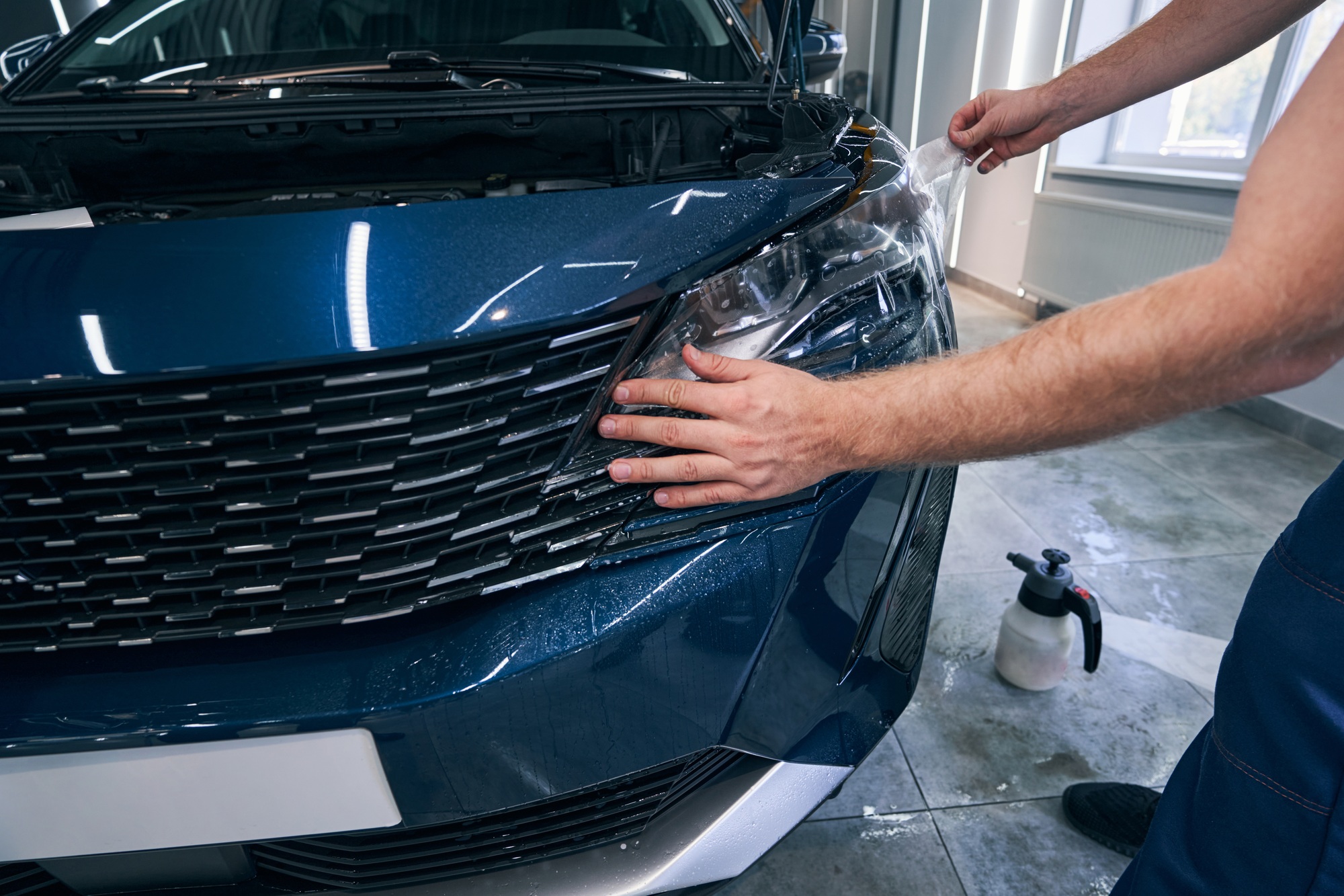 Closeup PPF installation on front headlight. Paint protection film